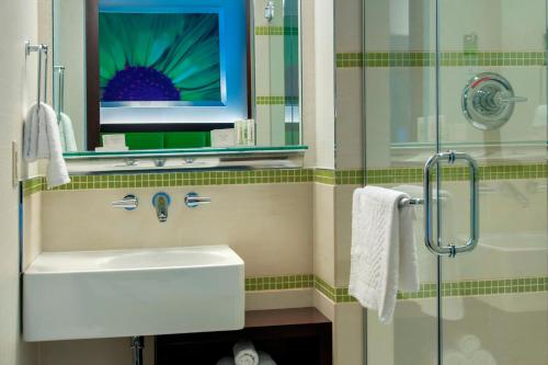 La salle de bains est pourvue d'un lavabo, d'un miroir et d'une douche. dans l'établissement SpringHill Suites by Marriott New York Midtown Manhattan/Fifth Avenue, à New York