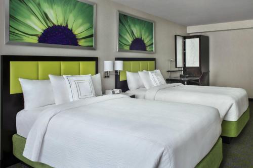 two beds in a hotel room with paintings on the wall at SpringHill Suites by Marriott New York Midtown Manhattan/Fifth Avenue in New York
