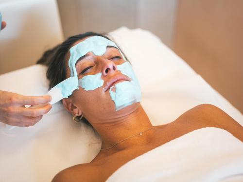 a woman laying in a bed with a mask on her face at Hotel Terme Millepini in Montegrotto Terme