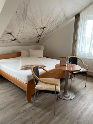 um quarto com uma cama, uma mesa e cadeiras em Landhotel Altmann em Hörstel