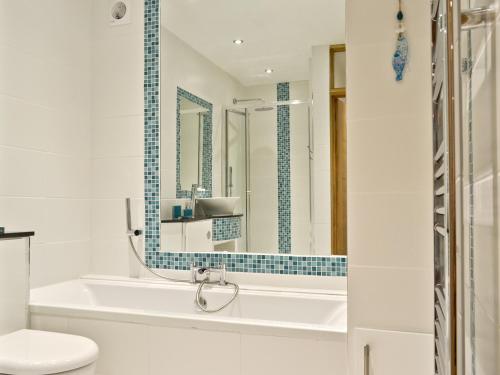 a bathroom with a tub and a toilet and a mirror at Florina in Cheriton Bishop