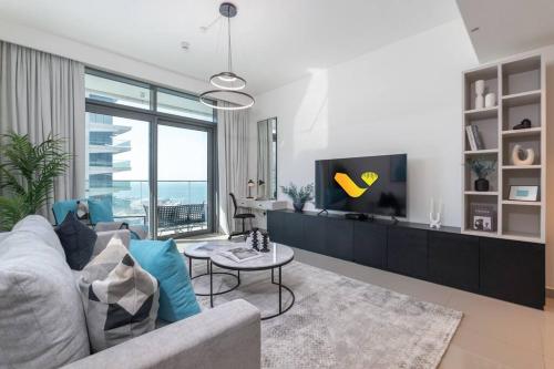 Una sala de estar con un sofá y un televisor. en Vogue Fascinating Beachfront One Bedroom Apartment with Balcony and Palm Views & Private Beach with full Amenities, en Dubái