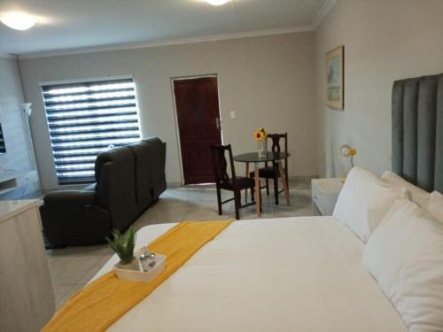 um quarto com uma cama branca, uma mesa e cadeiras em Bella's self contained daily accommodation em Meyerton