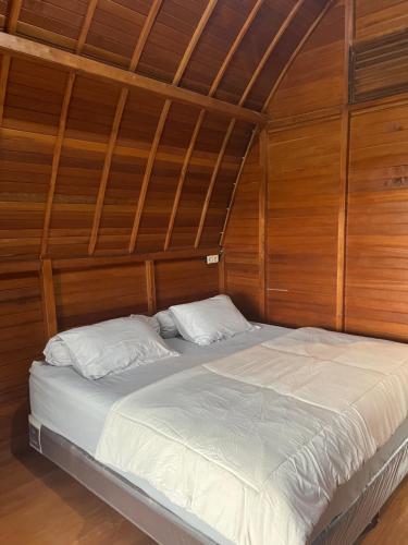 a bed in a room with wooden walls and ceilings at Vila Kopi Ciwidey in Ciwidey