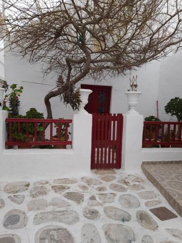 a white building with a red fence and a tree at Terra Nova in Mikonos