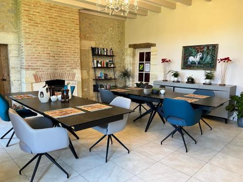 una sala da pranzo con tavoli neri e sedie blu di Ancien Haras de la Tour a Lamothe-Landerron