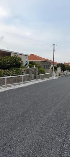 una calle vacía con una valla a un lado de la carretera en Sofi's House, en Ándros