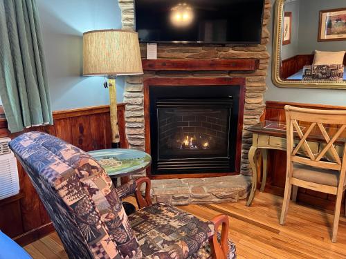 a living room with a fireplace with a couch and a chair at Homestead Inn - Blowing Rock in Blowing Rock