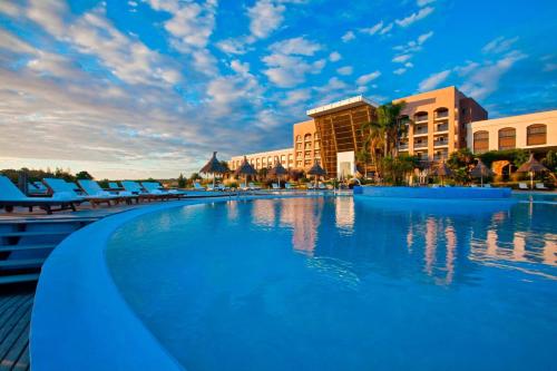 een zwembad in een resort met blauwe stoelen en gebouwen bij Sheraton Colonia Golf & Spa Resort in Colonia del Sacramento