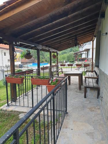 a covered patio with benches and a picnic table at Бадевски рай-къща Любов in Badewzi