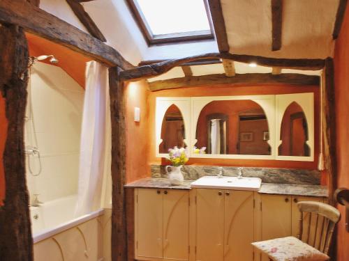 a bathroom with a sink and a tub and a mirror at Stable End in Halesworth