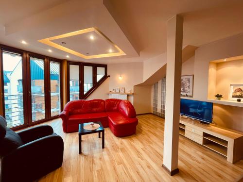 salon z czerwoną kanapą i telewizorem w obiekcie Apartament Słoneczny w Ostrowie Wielkopolskim