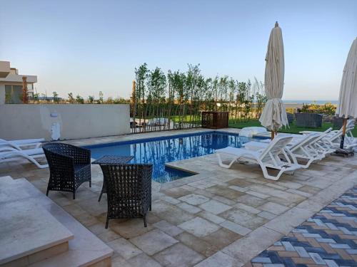 a swimming pool with chairs and an umbrella at Villa Fanadir, El Gouna in Hurghada