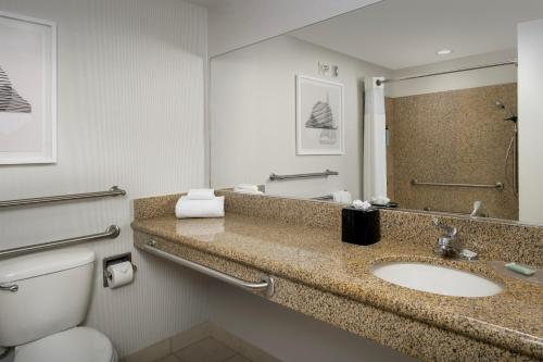 a bathroom with a sink and a toilet and a mirror at Courtyard by Marriott Seattle Kirkland in Kirkland