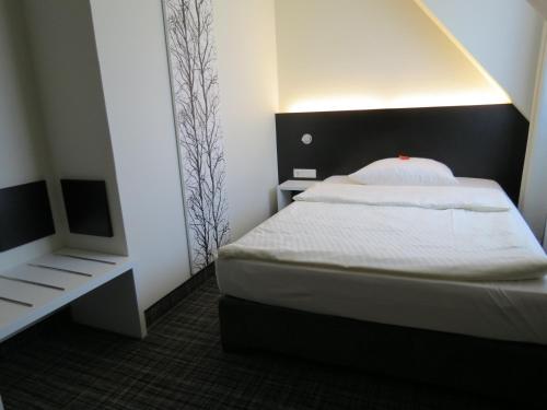 a small bedroom with a bed and a mirror at Comfor Hotel Ulm City in Ulm