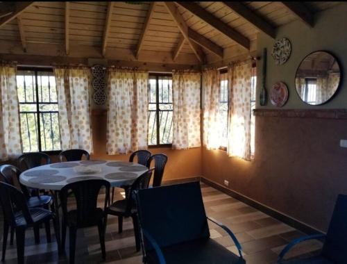 a dining room with a table and chairs and windows at Cabaña Agapanto Azul in Constanza
