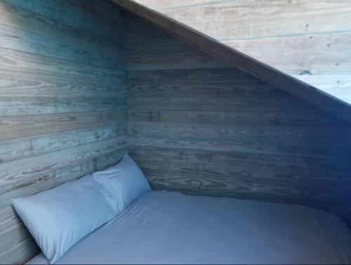 a bed in a room with a wooden wall at Cabaña Agapanto Azul in Constanza