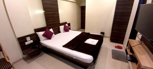 a bedroom with a bed with purple pillows and a tv at Hotel Orange in Vapi