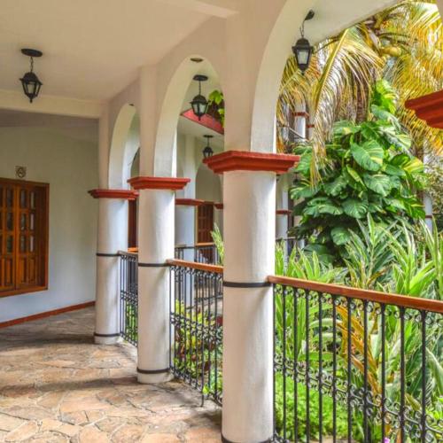 a porch of a house with columns and a fence at Hotel La Ceiba in Chiapa de Corzo