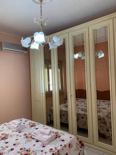 a bedroom with a bed and a chandelier and mirrors at Casa Fanù in Licata