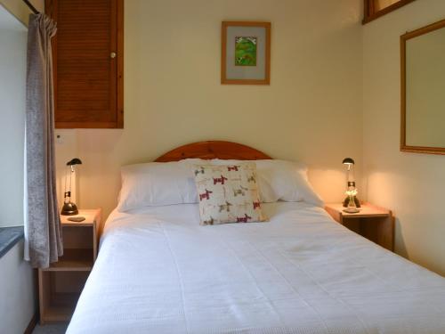 a bedroom with a large white bed with two lamps at The Smithy in Brentor