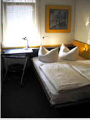 a hotel room with a bed and a desk and a window at Motel Pelikan in Dettelbach