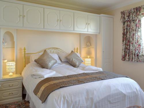 a bedroom with a large bed with white sheets and pillows at Meadowcroft in Llanllwchaiarn