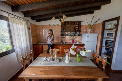 a woman standing in a kitchen talking on a cell phone at Casa Rural Sofia in Hermigua