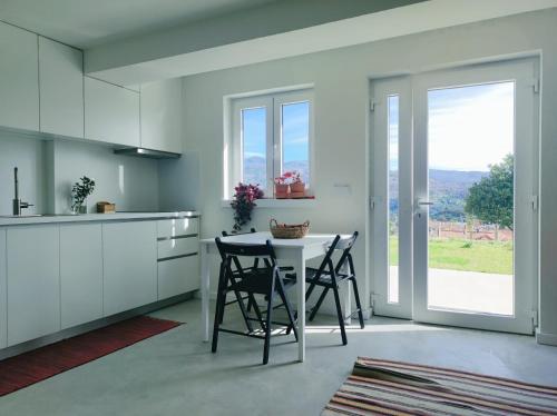 uma cozinha branca com uma mesa e cadeiras e uma janela em Casa do Crasto em Soajo