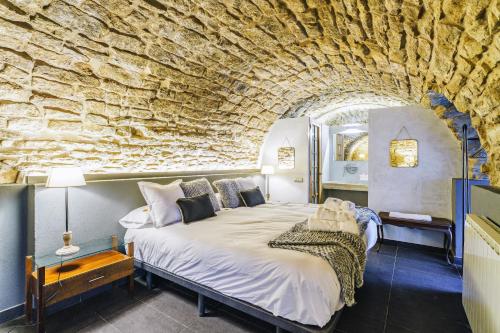 a bedroom with a large bed in a stone wall at Masia de Queralt Luxury Casa Rural Spa y Vistas in Concabella