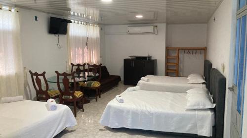 a room with three beds and a chair and a television at Hotel El Broche in Yopal