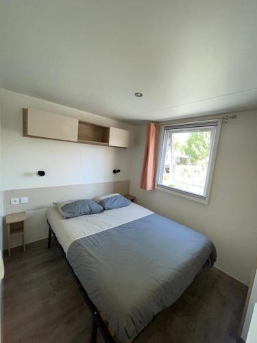une chambre avec un grand lit avec une fenêtre dans l'établissement Valras-Plage, les sables du midi ,mobil home, à Sérignan