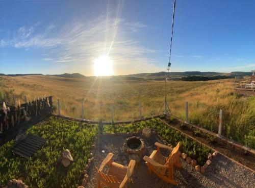 a view of the sun setting over a field with chairs at Cabana Cambará in Cambara do Sul