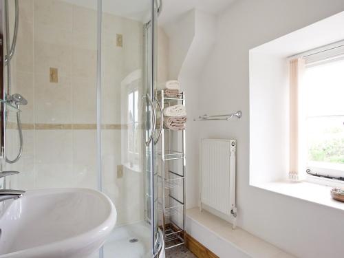uma casa de banho branca com um lavatório e um chuveiro em Rose Cottage em Cold Ashton