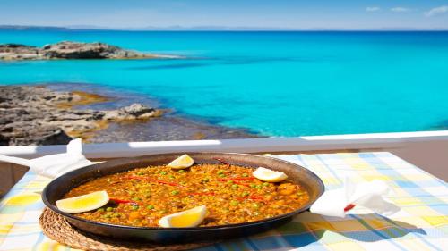 a pan of food on a table next to the ocean at Catalunya Casas Blissful Costa Dorada Escape with private pool in Bisbal del Penedès