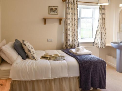 a bedroom with a bed with a tray of food on it at Farm Cottage annex in Smallburgh