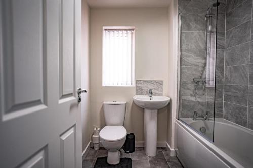 a bathroom with a toilet and a sink and a tub at Stunning canal view 2 bedroom home with free parking in Manchester