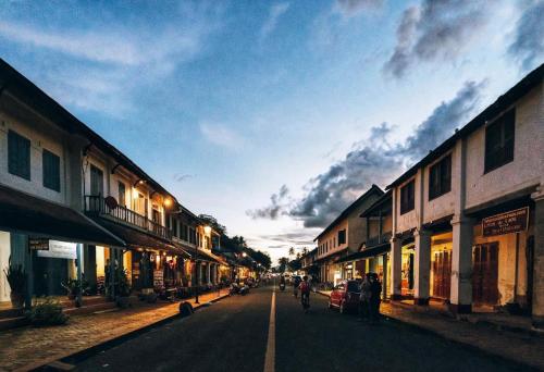 a street in an old town with people riding bikes at Villa KiengKham晶康民宿 in Luang Prabang