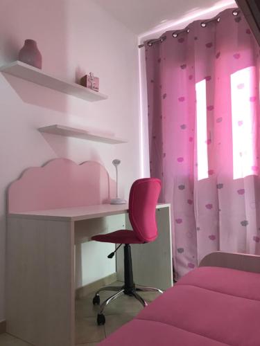 a pink bedroom with a desk and a chair at Domu Bonora in Pula