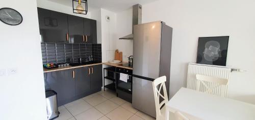 a kitchen with black cabinets and a stainless steel refrigerator at LOTUS- 4 min de Walt Disney-Arrivée autonome-Parking et Wifi gratuit-Proche de toutes commodités 5Min de la vallée village in Chessy