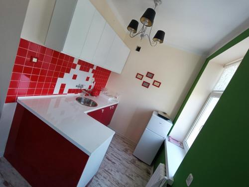 - une cuisine rouge et blanche avec évier et réfrigérateur dans l'établissement Green Apartment Tumska, à Płock