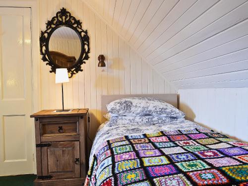 a bedroom with a bed with a quilt and a mirror at Isle View - 28284 in Broadford