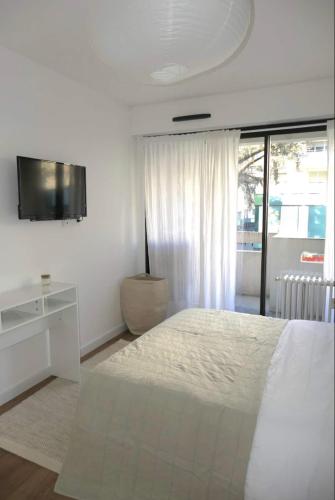 a white bedroom with a bed and a tv at M007-8-9 Marquer Chambre colocation proche de la Gare in Annemasse