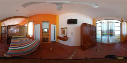 Cette chambre dispose d'un lit, d'une télévision et de quelques fenêtres. dans l'établissement El Tucan, à Puerto Escondido