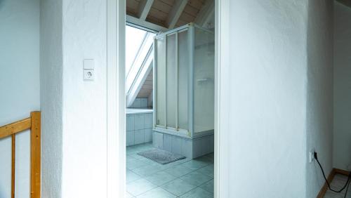 La salle de bains est pourvue d'une porte en verre menant à une douche. dans l'établissement FeWo WOW II Schöne 2-Zimmer Maisonette Wohnung, à Weisweil