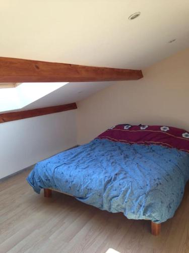 a bed with a blue comforter in a bedroom at Joli T3 en Centre Village de Tallard in Tallard