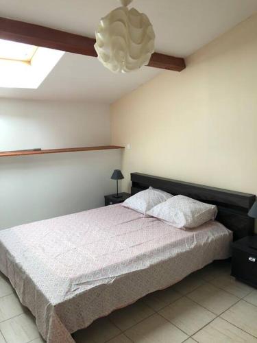 a bedroom with a large bed and a chandelier at Joli T3 en Centre Village de Tallard in Tallard