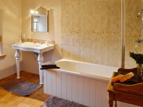 a bathroom with a tub and a sink and a shower at Higher Thorne Cottage - 28297 in Warleggan