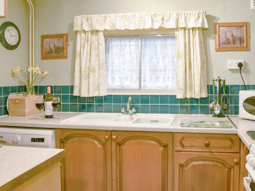 a kitchen with a sink and a window at Woodbine Cottage in Ludham