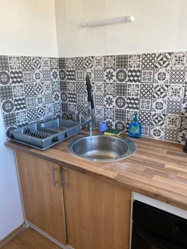 a kitchen counter with a sink and a tile wall at Appartement 1 chambre moderne à proximité du circuit des 24h in Le Mans